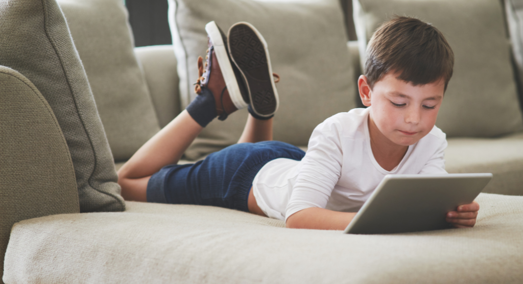 A boy laying on the couch online.