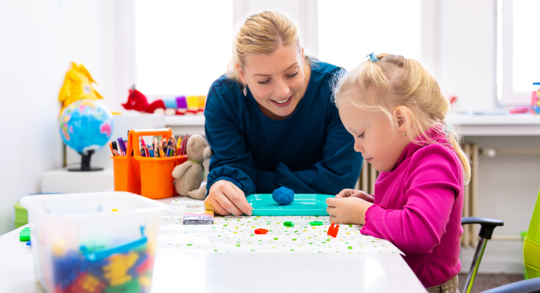 A teacher working with a student with clay.