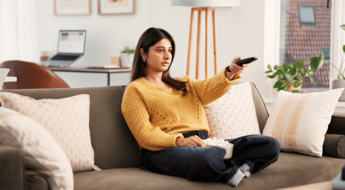 Love Story A woman on the couch with a TV remote and popcorn.