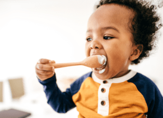 A toddler eating off of a spoon.