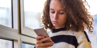 A teen looking at a cell phone.