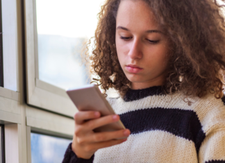 A teen looking at a cell phone.