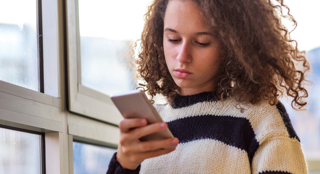 A teen looking at a cell phone.