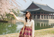A woman reaching out to touch a cherry blossom.
