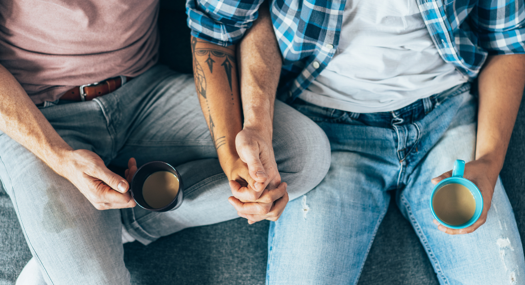 Gay men holding hands and drinking coffee. 