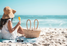 A woman sitting on the beach eating a Popsicle.