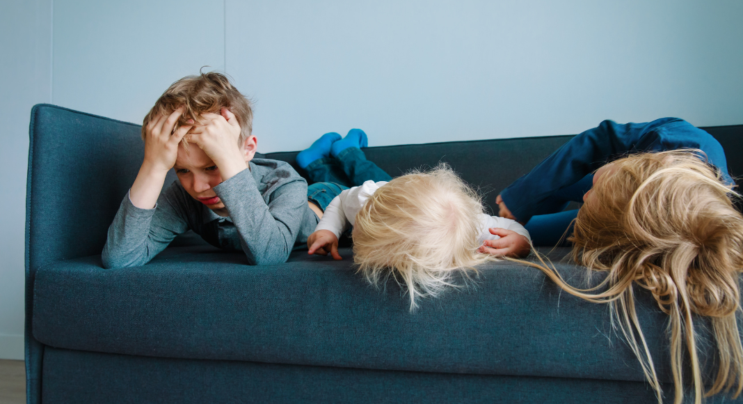 Children laying on a couch bored. 