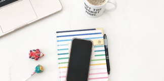 A phone placed on an agenda book next to a computer and coffee.